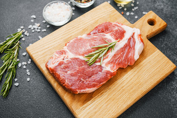 Raw beef steak with rosemary and spices on wooden board
