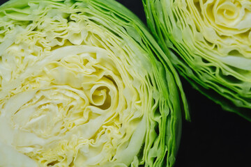 Two cut cabbage halves on dark background close detail