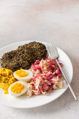 A hearty, healthy, and balanced breakfast with quinoa pancakes, fresh cabbage and radish salad with mung bean sprouts, boiled eggs, hummus, and cooked beets, offering a rich source of protein