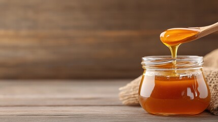 A close-up view of golden honey pouring from a wooden spoon into a glass jar, showcasing its rich texture and natural sweetness, perfect for culinary delights.