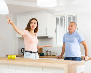 Domestic quarrel between elderly father and adult daughter in the kitchen