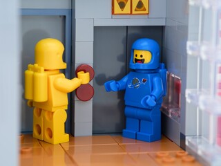 Obraz premium Tambov, Russian Federation - May 26, 2025 Two Lego astronaut minifigures waiting at an elevator. The yellow one is pressing a button on the elevator.