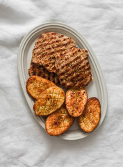 Pork chops, grilled turkeys and baked potatoes - delicious lunch, dinner on a light background, top view