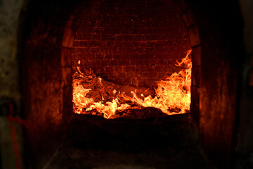Close-up view of blazing fire inside a temple furnace burning joss paper during a traditional...