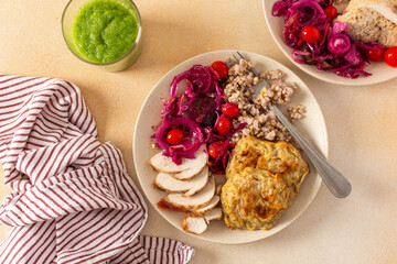 A healthy meal of green buckwheat with chicken breast, zucchini pancakes, fermented vegetable...