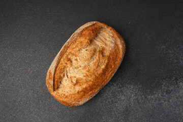 Freshly baked artisan bread loaf on dark countertop