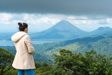 woman observing Arenal volcano from mountain viewpoint