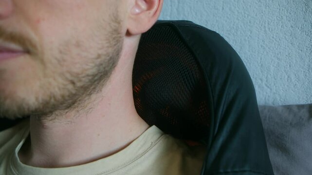 Close up of heating pad resting on man's neck and shoulders, delivering soothing warmth and providing targeted relief from muscle tension and persistent pain