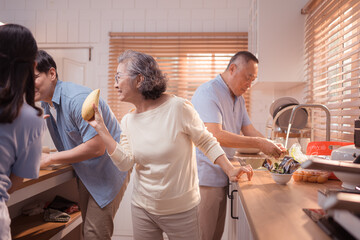 Obraz premium Happy Asian family preparing food together in a bright kitchen