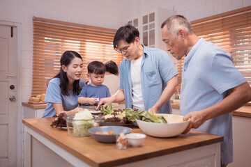 Happy Asian family preparing food together in a bright kitchen,