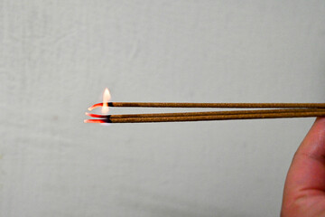 Taiwan June 2, 2025: A hand holding freshly lit incense sticks used in prayer or ancestral tribute