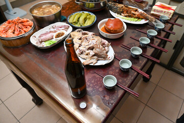 Overhead view of a full Taiwanese family feast with seafood, meats, soup, and traditional side dishes arranged neatly on a wooden table