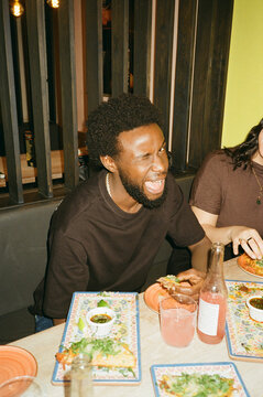 Portrait of young man winking while eating tacos at fast food restaurant