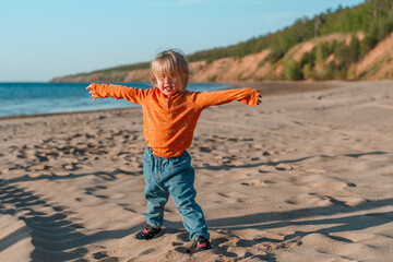 Cute little child on a sandy beach with a beautiful landscape