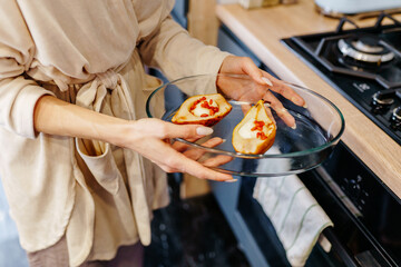Close up of mother in her 40s holding baking dish with stuffed pears