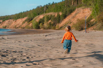 Cute little child on a sandy beach with a beautiful landscape
