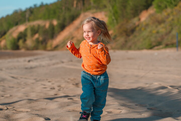 Cute little child on a sandy beach with a beautiful landscape