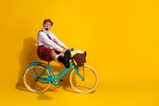 Elderly Scottish Man on Bike Having Fun in a Traditional Outfit With Yellow Background for Joyful Concepts and Promotions