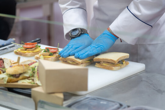 Chef preparing sandwiches with gloves in a kitchen setting