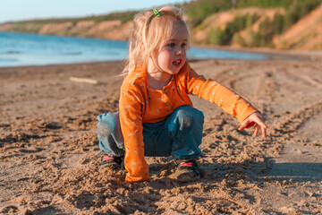 Cute little child on a sandy beach with a beautiful landscape
