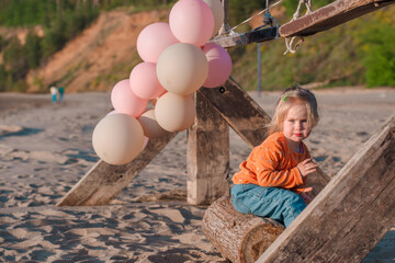 Cute little child runs with balloons by the sea with beautiful scenery