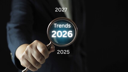 Businessman analyzing trends 2026 with magnifying glass strategic growth planning and digital innovation for business development