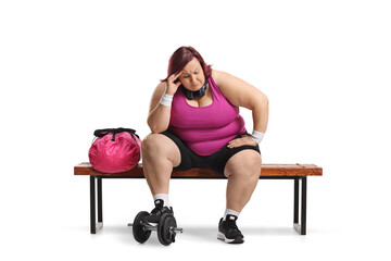 Tired overweight woman in sportswear sitting on a gym bench