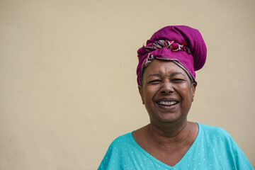 Happy senior african woman smiling on camera with neutral background in the city - Elderly lady wearing traditional dress and turban - Copy space