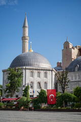A domed building and minaret, part of the ancient Hagia Sophia, Istanbul, Turkey. A large Turkish flag is hanging outside the building