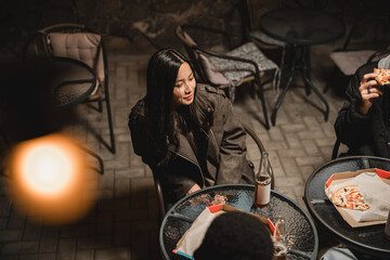 Group of friends enjoying food and drink outside at night in a cozy atmosphere