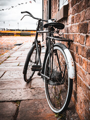 Vintage bicycle leaning against a brick wall on a cobblestone street.