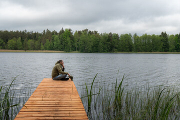 Thoughtful Man Alone by Forest Lake Holding Cap – Contemplation, Stillness and Inner Dialogue