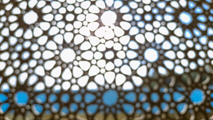 Blurry photo of an intricately designed decorative screen with a geometric pattern composed of...
