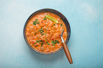 Delicious brazilian moqueca de camarao with shrimps, peppers, lime, and cilantro served in a bowl, garnished with parsley and served in a rustic bowl on light blue background