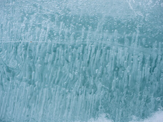 Fresh greenish ice with bubbles of air inside on the lake in winter