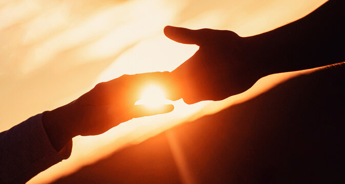 Hands help in trouble. Man giving hand to man outdoors at sunset, closeup. Help and support concept. Closeup helping hands on the sunset sky background
