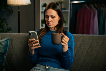 Woman Relaxing on Sofa Enjoying Coffee and Smartphone Interaction