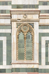 Gothic bifora window with twisted columns and lion relief on the marble facade of Florence...