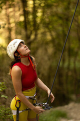 A woman in a red top and yellow shorts is holding onto a rope