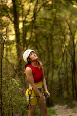 A woman in a red top and yellow shorts is looking up at something