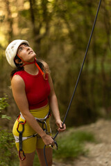 A woman in a red top and yellow shorts is holding onto a rope