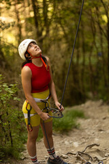 A woman in a red top and yellow shorts is holding onto a rope