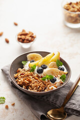 Homemade crispy granola, yogurt, fruits and berries in bowl on white background. Healthy breakfast