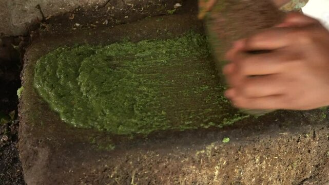 Hand‑held stone grinder: robust mortar and pestle, textured bowl crushes spices, seeds into fragrant, rustic powder or paste using manual pounding