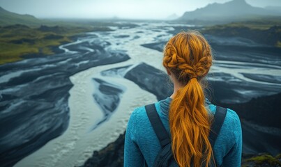 Woman contemplates a winding river in a volcanic landscape