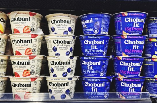Chobani Greek yogurts displayed on a grocery shelf, including strawberry, blueberry, and high-protein options in white and dark blue packaging. Healthy dairy. Malaysia, Kuala Lumpur- May, 2025