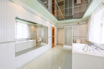 spacious bathroom with white tiled walls, a large mirror, bathtub, shower enclosure, and a mirrored ceiling reflecting the room. The floor is tiled in a light green