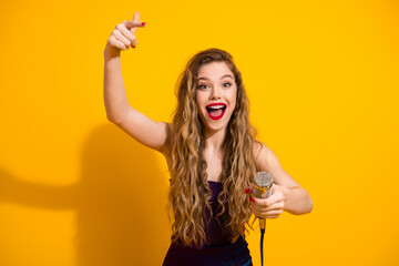 Excited young woman holding a microphone against a bright background showcasing joy and energy