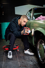 Young man using professional buffer tool to polish car