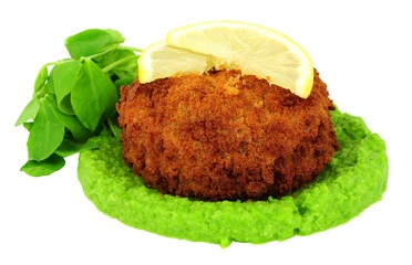 Breadcrumb covered fish cake filled with cod and creamy mashed potato with vivid green pea puree and pea shoot salad leaves isolated on a white background